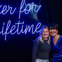 Girl and President Mantella stand in front of Laker for a Lifetime neon sign